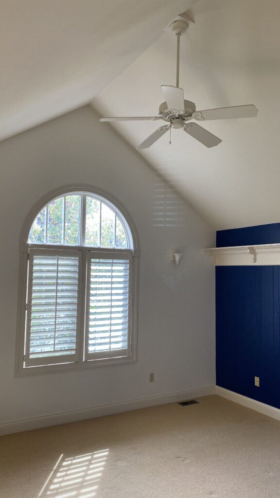 Spacious room with blue accent wall, white ceiling fan, and arched window painted by Franc Painting in Akron, OH.