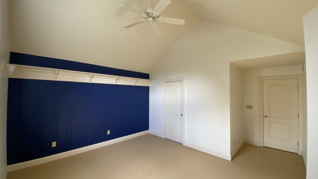 Deep blue accent wall in a high-ceiling room with white trim work by Franc Painting.