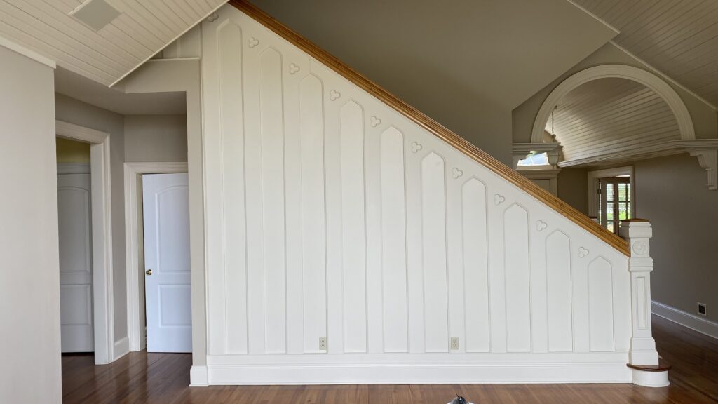 White stairwell with wood handrail and custom trim details painted by Franc Painting.