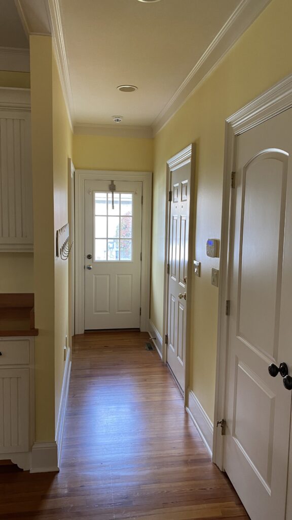 Hallway with soft yellow walls, white doors, and wooden floor by Franc Painting in Akron, Ohio.