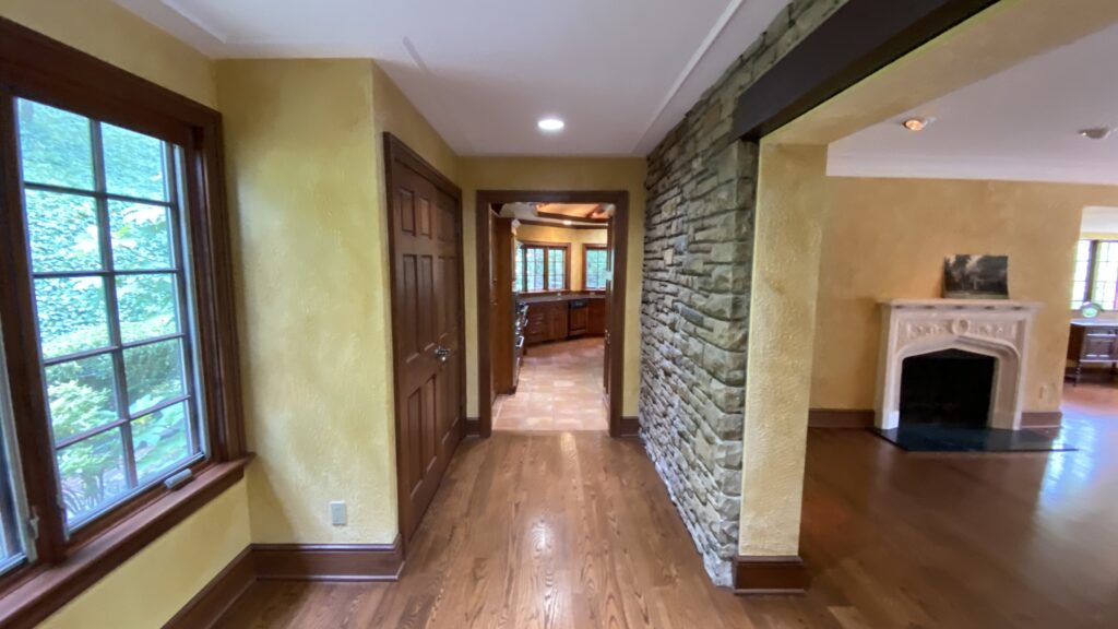 Hallway in Akron home painted with warm yellow tones and a stone accent wall by Franc Painting.