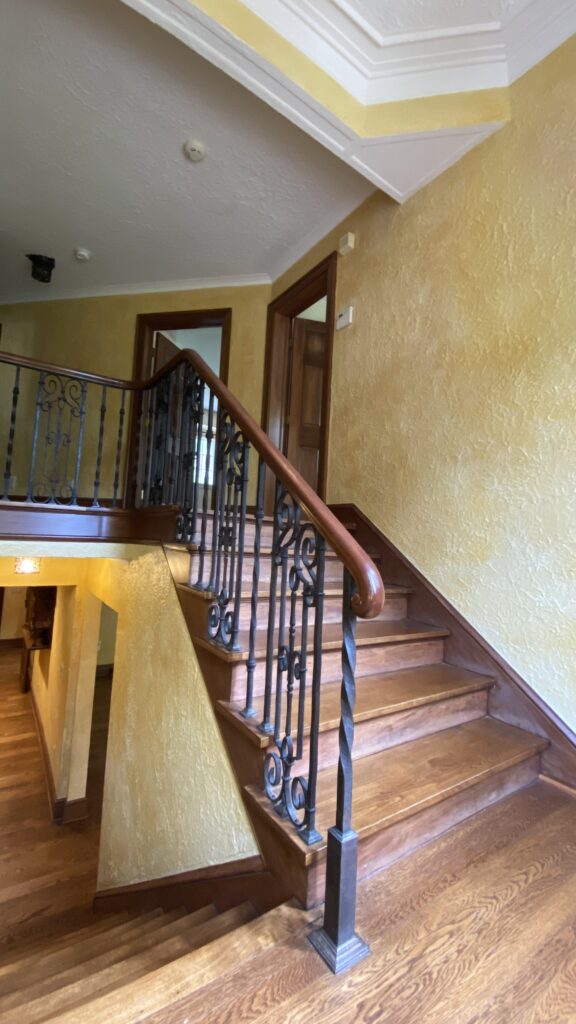 Wooden staircase with wrought iron railing and textured walls painted by Franc Painting in Akron, Ohio.